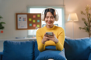 Happy freelancer enjoying music and browsing social media on her phone while working from home