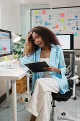 Stressed businesswoman reading bad news on a clipboard while sitting at her desk in the office