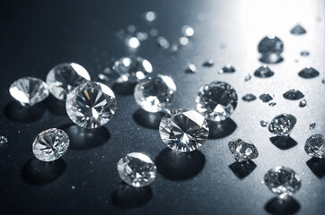 Brilliant diamonds are scattered across a dark surface, reflecting light and creating mesmerizing sparkles and glimmers. Their clarity and cut are prominently displayed