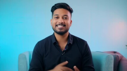Indian guy records video blog, talks on camera. Male blogger shoots vlog at home on phone. Popular vlogger influencer. Social media communication. Blue neon light. Man in black shirt.