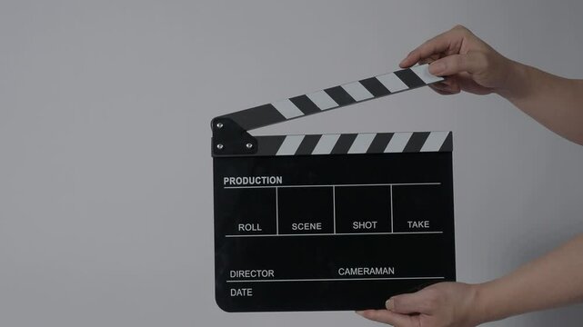 Movie slate or clapperboard hitting with recording frame. Close up hand holding empty film slate and clapping in front of camera clear background. Open and close film slate filming a video production
