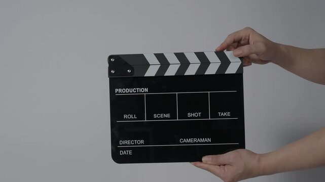 Movie slate or clapperboard hitting with recording frame. Close up hand holding empty film slate and clapping in front of camera clear background. Open and close film slate filming a video production