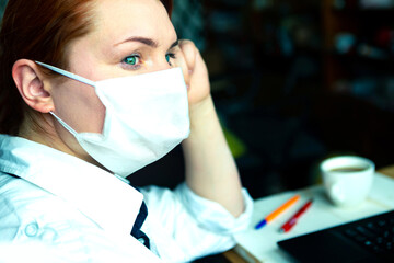 Redhead girl in face mask looking out the window. Stay home quarantine concept