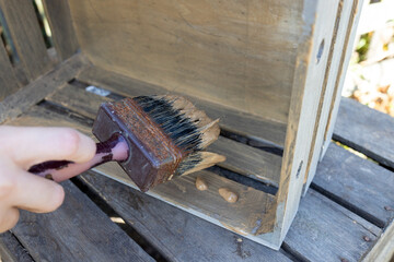 a child paints a wooden box with brushes in the garden