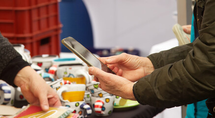 A customer at a farmers market takes photos of the goods on display with his smart phone.