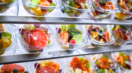 Boxes with pre-packaged fruit salads in a commercial fridge