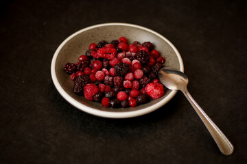 A ceramic bowl filled with frozen mixed berries