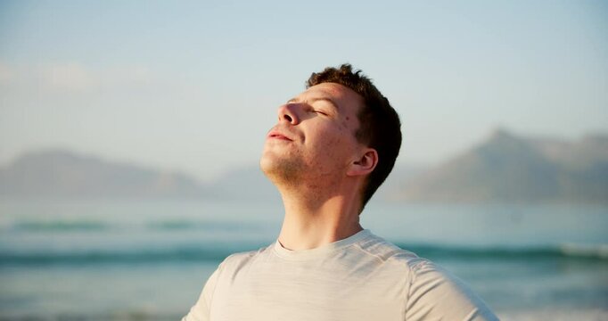 Man, relax and breathing with fitness on beach for peace, health and wellness by sea in nature. Young, male person or athlete with smile for natural fresh air, breeze or mindfulness on ocean coast