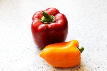 There is a red bell pepper and a yellow bell pepper resting on a counter