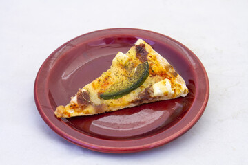 A slice of cold pizza on a side plate isolated on a clear background with copy space