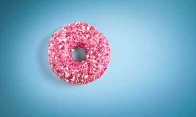 Donut in pink glaze on blue background, top view