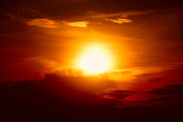 This is a beautiful sunset or sunrise photo with bright orange, yellow, and red as the main colors in the sky. The sun is partially obscured by clouds, which makes the sky look brighter and warmer.