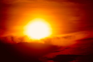 This is a beautiful sunset or sunrise photo with bright orange, yellow, and red as the main colors in the sky. The sun is partially obscured by clouds, which makes the sky look brighter and warmer.