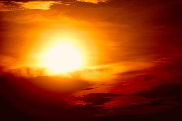 This is a beautiful sunset or sunrise photo with bright orange, yellow, and red as the main colors in the sky. The sun is partially obscured by clouds, which makes the sky look brighter and warmer.