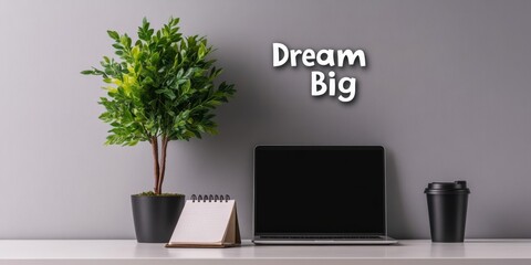 The slogan "Dream Big" on the background of a simple desktop with a laptop and notepad