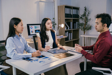 Business team discussing and brainstorming, analyzing sales data chart using tablet and computer in the meeting room, during a corporate meeting