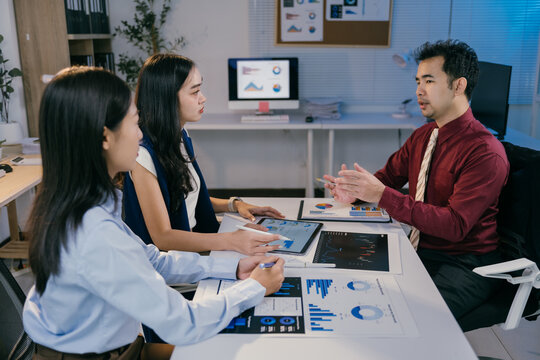 Business team discussing and analyzing financial charts and reports using digital tablet and printed documents during a productive office meeting