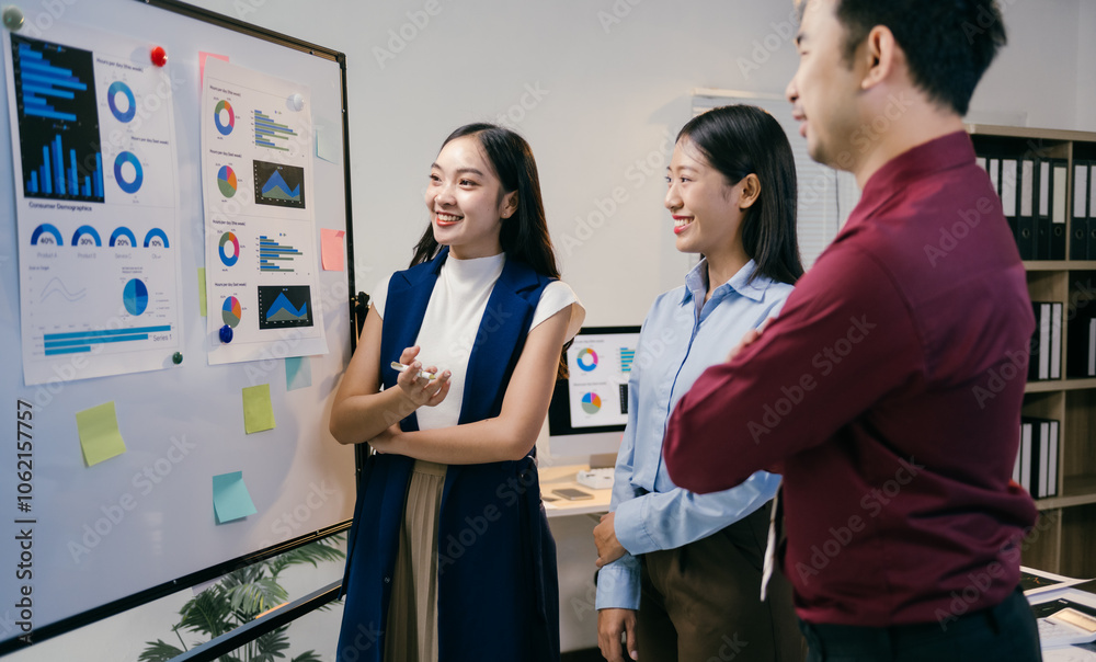Aufkleber three asian businesspeople are discussing charts and graphs on a whiteboard during a productive meet