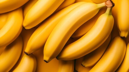 A bunch of yellow bananas are piled on top of each other. The bananas are ripe and ready to eat