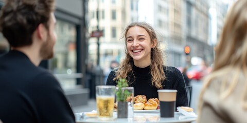 Young woman smiling with friends at a cafe table in a city street.