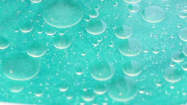 Una toma de cerca de varias burbujas de agua y aceite en movimiento en un fondo de color azul claro