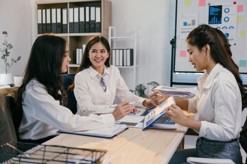 Three asian businesswomen are analyzing financial reports and charts in a well-lit office, demonstrating teamwork and expertise in business management