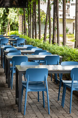 A cozy outdoor dining area. Wooden tables, stools, and chairs set up at an outdoor cafe on a sunny summer day.
