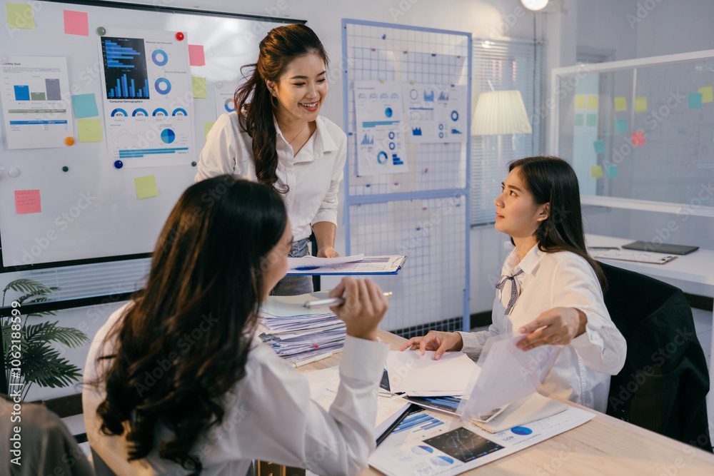 Poster three asian businesswomen are analyzing charts and documents, collaborating on a project in a modern