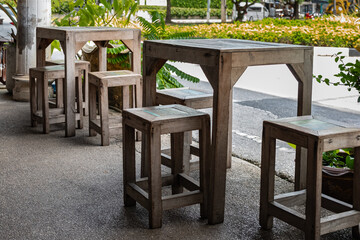 A cozy outdoor dining area. Wooden tables, stools, and chairs set up at an outdoor cafe on a sunny summer day.
