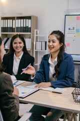 Businesswomen are discussing new business strategies and opportunities while sitting at a table in a modern office, collaborating and working together on a project