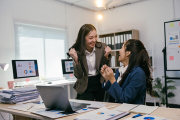 Two excited businesswomen are celebrating a successful business achievement in a modern office, expressing joy and teamwork
