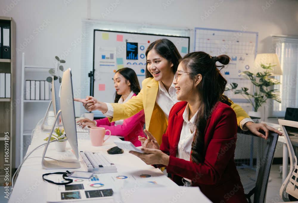 Poster three asian businesswomen are smiling and collaborating on a computer project, pointing at the scree