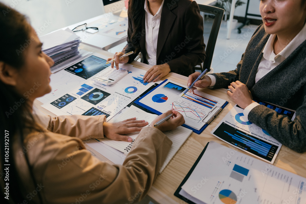 Poster Businesswomen are having a meeting analyzing financial charts and graphs using a calculator and taking notes in a notebook, discussing company strategy and planning