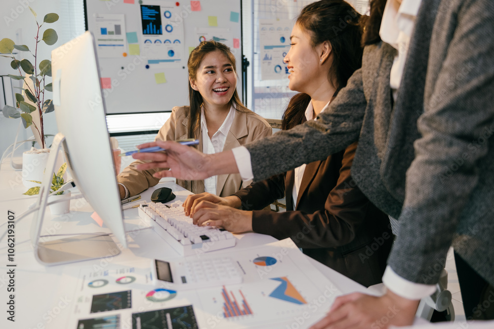 Poster Asian businesswomen are collaborating on a project, analyzing charts and graphs displayed on a computer screen, discussing strategies and sharing insights in a modern office environment