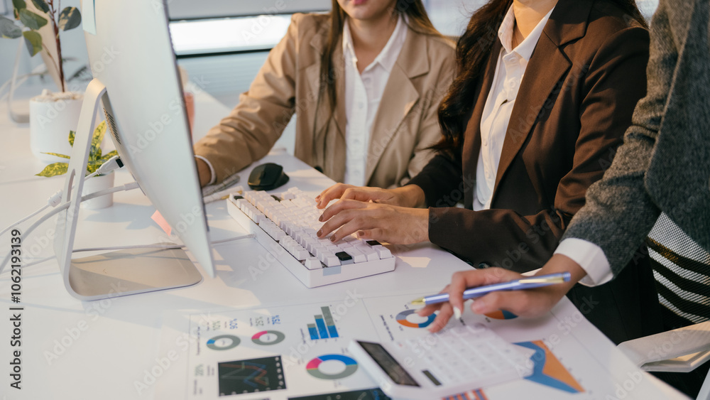 Aufkleber Businesswomen are typing on a computer keyboard and analyzing financial charts and graphs, collaborating on a project in a modern office