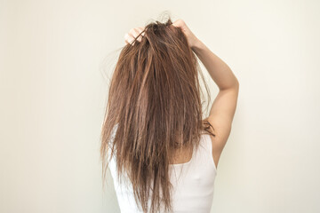 Fototapeta premium Damaged hair, frustrated asian young woman, girl in splitting ends, messy unbrushed dry hair and frizzy with long disheveled hair, health care of beauty. Portrait isolated on background, Back view.