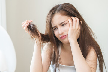 Damaged Hair, frustrated asian young woman, girl hand in holding splitting ends, messy unbrushed...