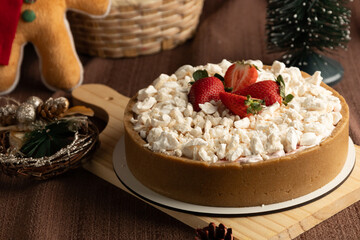 Rustic strawberry meringue tart with a crumbly cookie crust, topped with crushed meringue and fresh strawberries, set in a festive holiday setting with pinecones and Christmas ornaments.