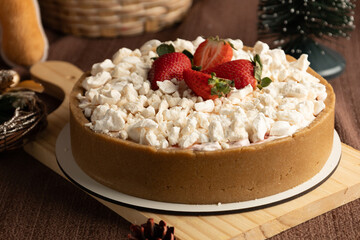 Rustic strawberry meringue tart with a crumbly cookie crust, topped with crushed meringue and fresh strawberries, set in a festive holiday setting with pinecones and Christmas ornaments.