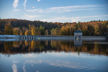 Lac des Settons dam in the Morvan in Burgundy, France, in autumn with a forest of red and yellow trees