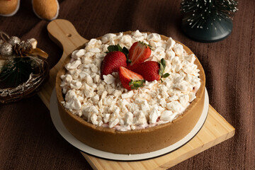 Rustic strawberry meringue tart with a crumbly cookie crust, topped with crushed meringue and fresh strawberries, set in a festive holiday setting with pinecones and Christmas ornaments.