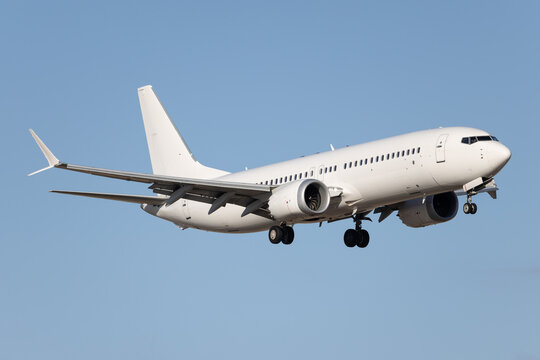 White modern airliner landing at airport.