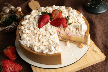 Rustic strawberry meringue tart with a crumbly cookie crust, topped with crushed meringue and fresh strawberries, set in a festive holiday setting with pinecones and Christmas ornaments.