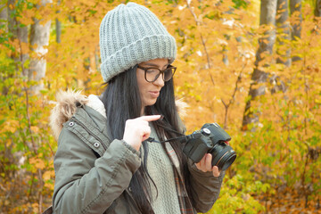 A young, beautiful girl travels in nature, admires the beauty of the autumn forest with admiration,...