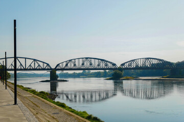 Old railroad bridge, on the Vistula River .On the left along the bank is an embankment with lanterns.