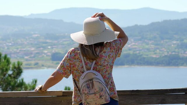 Tourist woman enjoying the views of the Galician coast from the top of a mountain viewpoint, Pontevedra.
