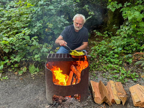 Senior man cooking potatoes on a campfire, British Columbia, Canada