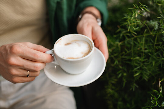 Close-up overhead view of a Man sitting at an outdoor cafe drinking a cappuccino