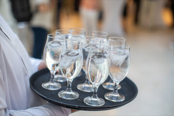 Waiter carrying a tray of water glasses at formal event
