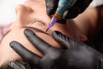 Beautician applying permanent eyebrow makeup on woman's face
